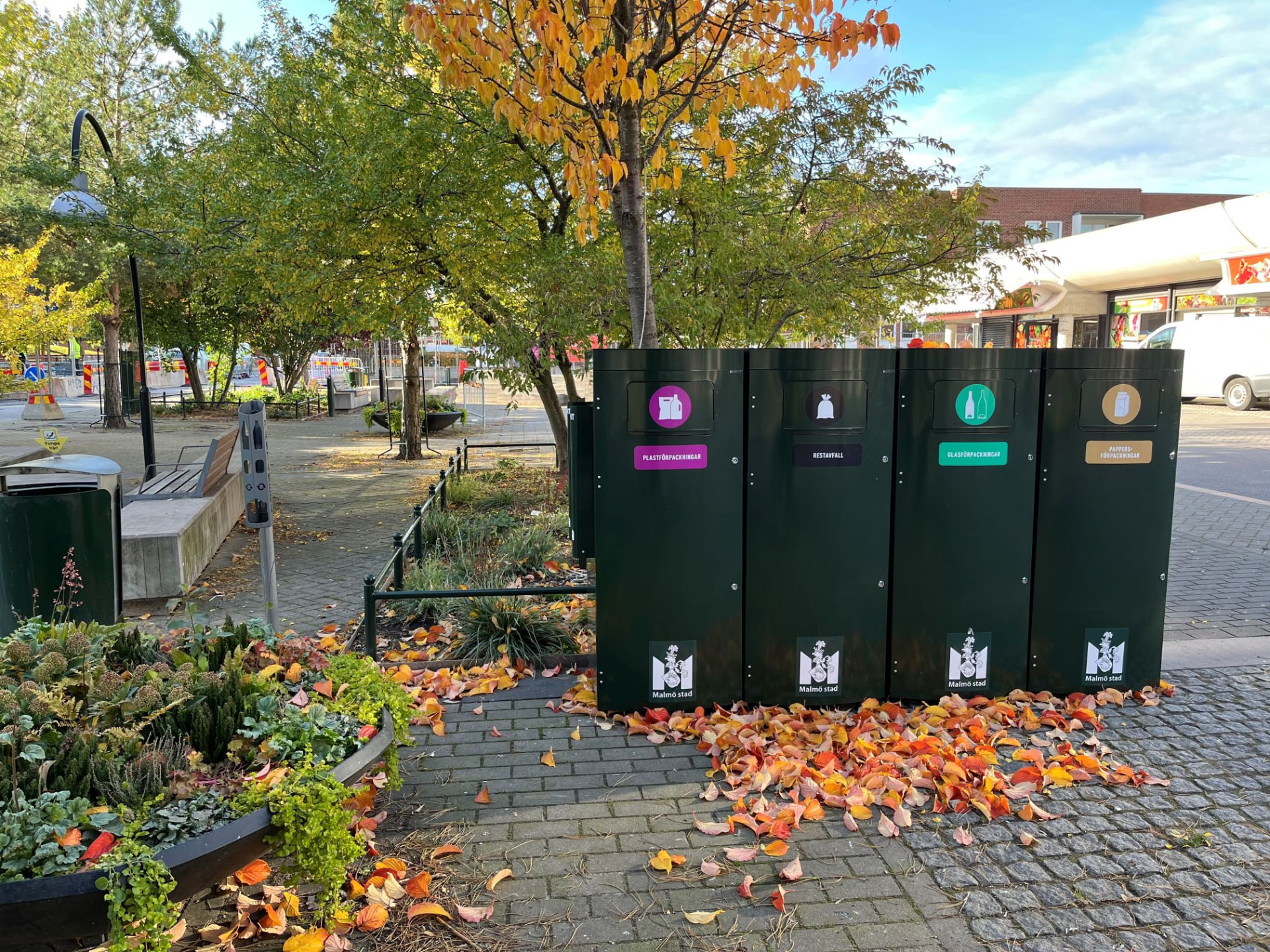 Mörkgröna Sortify källsorteringskärl på en parkyta i Malmö under hösten