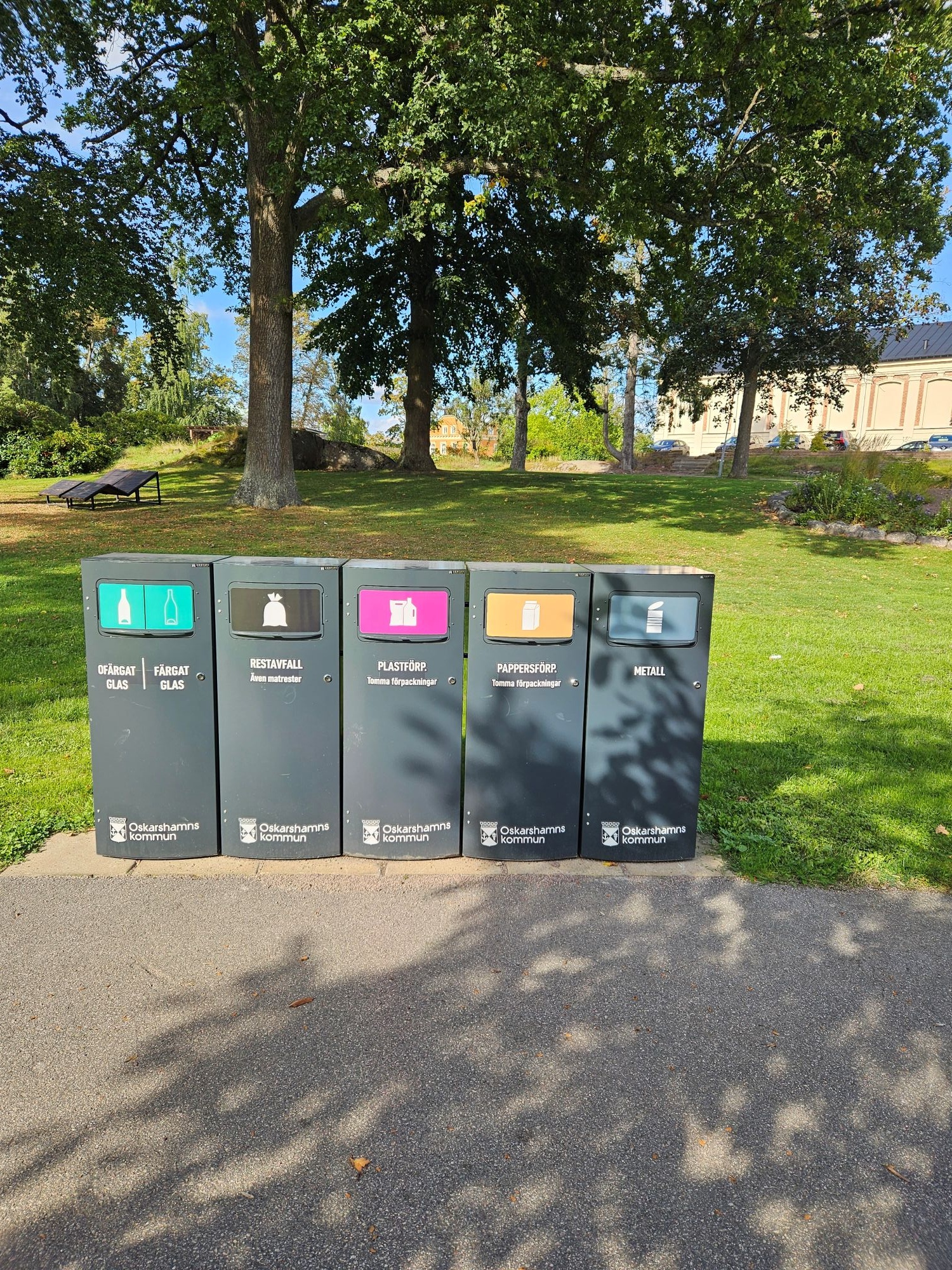 Fem grå Mango M-kärl för glas, restavfall, plast, papper och metall i en park i Oskarshamn