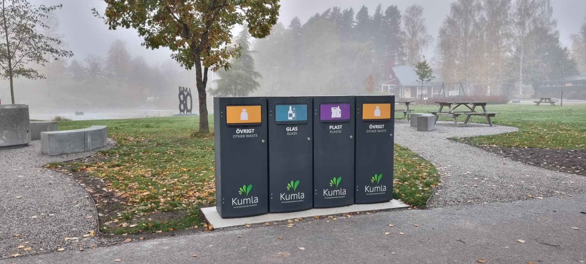 Fyra mörka Sortify Mango M kärl för glas, plast och övrigt avfall i en park i Kumla