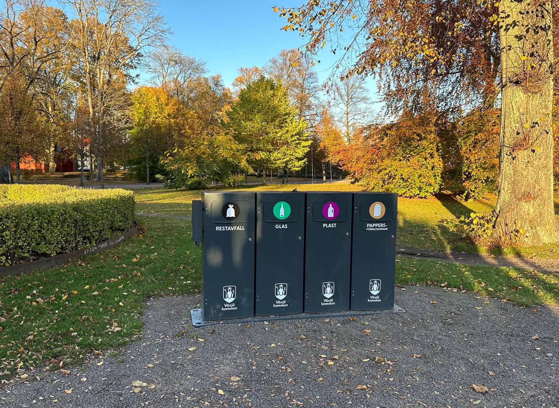 Fyra mörka Mango M avfallskärl för restavfall, glas, plast och pappersförpackningar i en park i Växjö