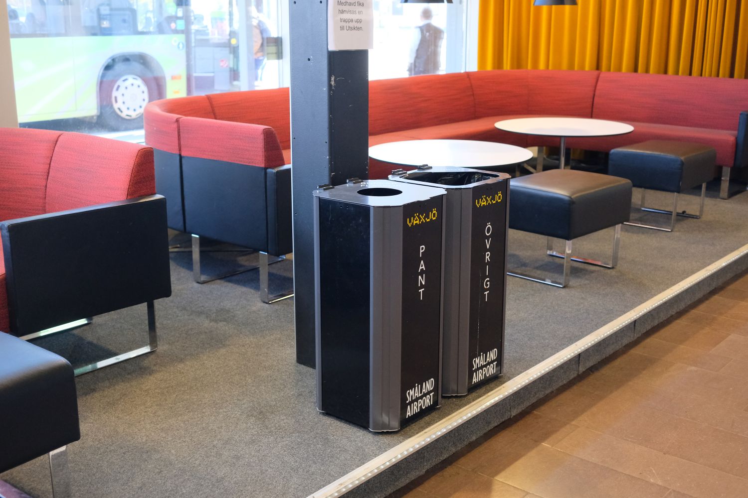 Två svarta Kiwi kärl för pant och övrigt vid en soffgrupp i caféytan på Småland Airport