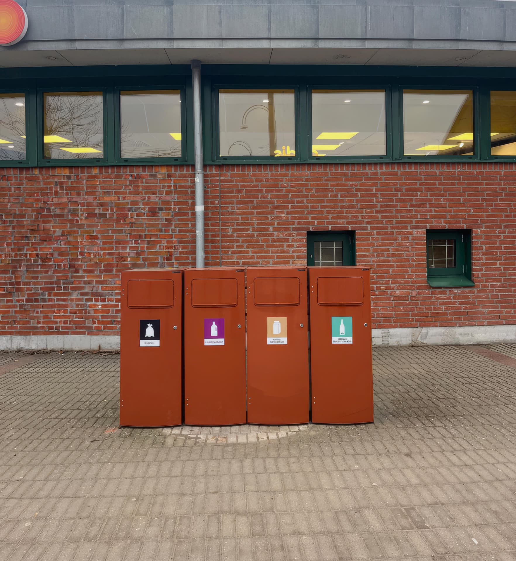 Fyra bruna Mango M-kärl framför en tegelfasad i Landskrona
