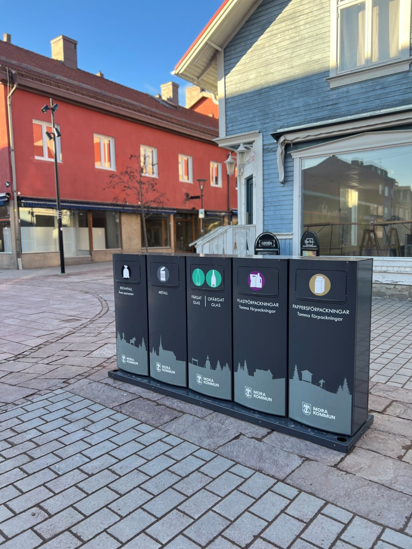 Fem Sortify Mango kärl med Mora kommuns siluettmotiv på en gågata