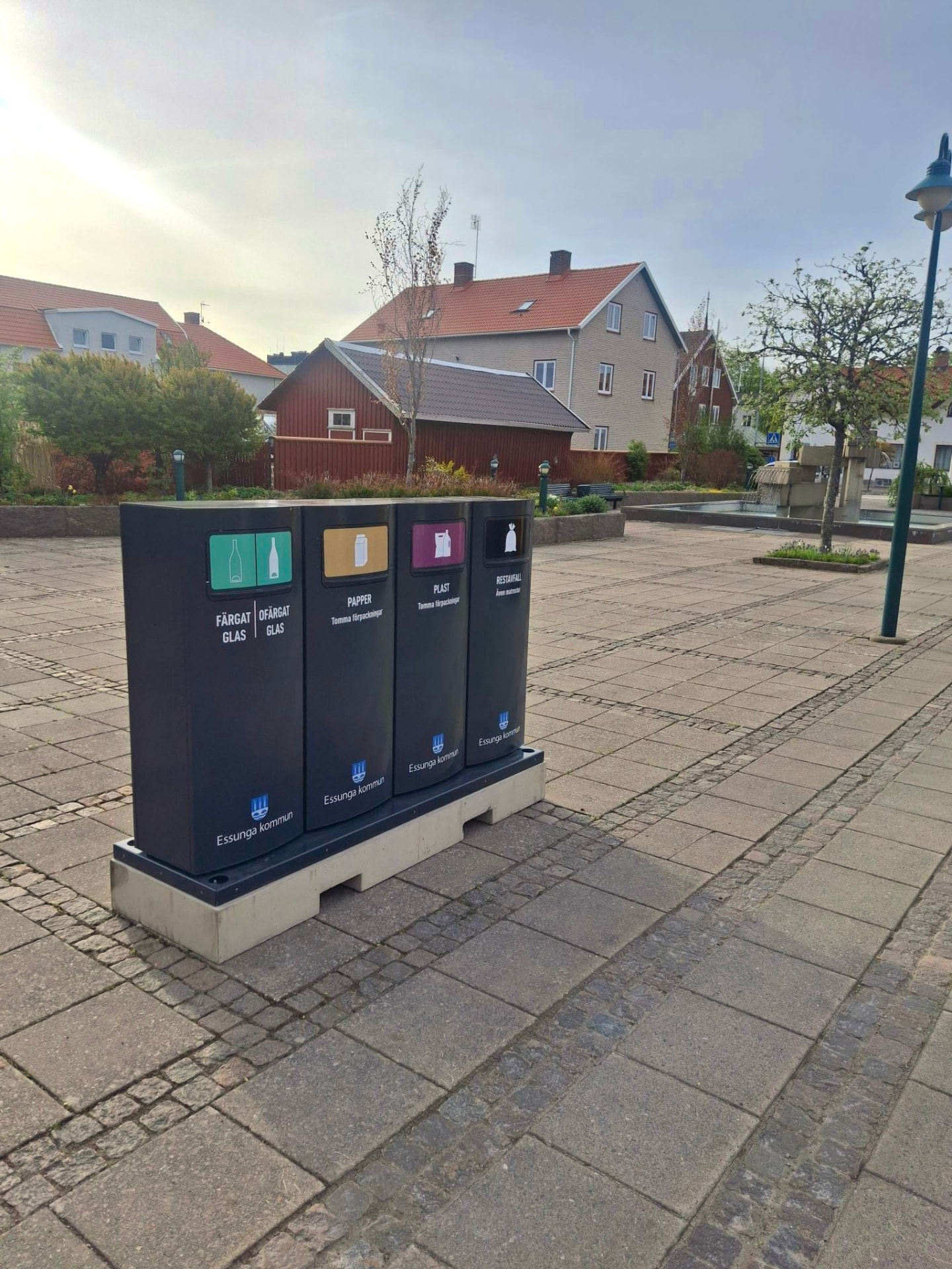 Fyra Mango M kärl med Essunga kommuns märkning på ett gemensamt fundament på en torgyta
