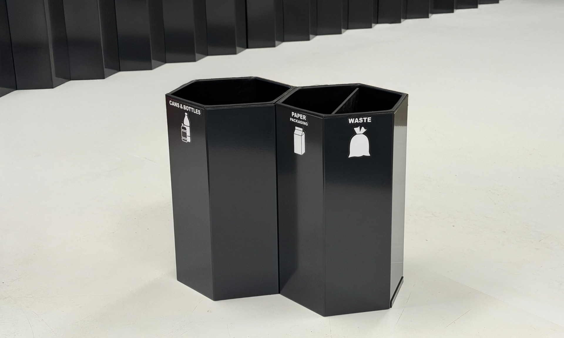 Två mörka Papaya kärl märkta Cans & bottles, Paper packaging och Waste i en ljus inredd hotellmiljö